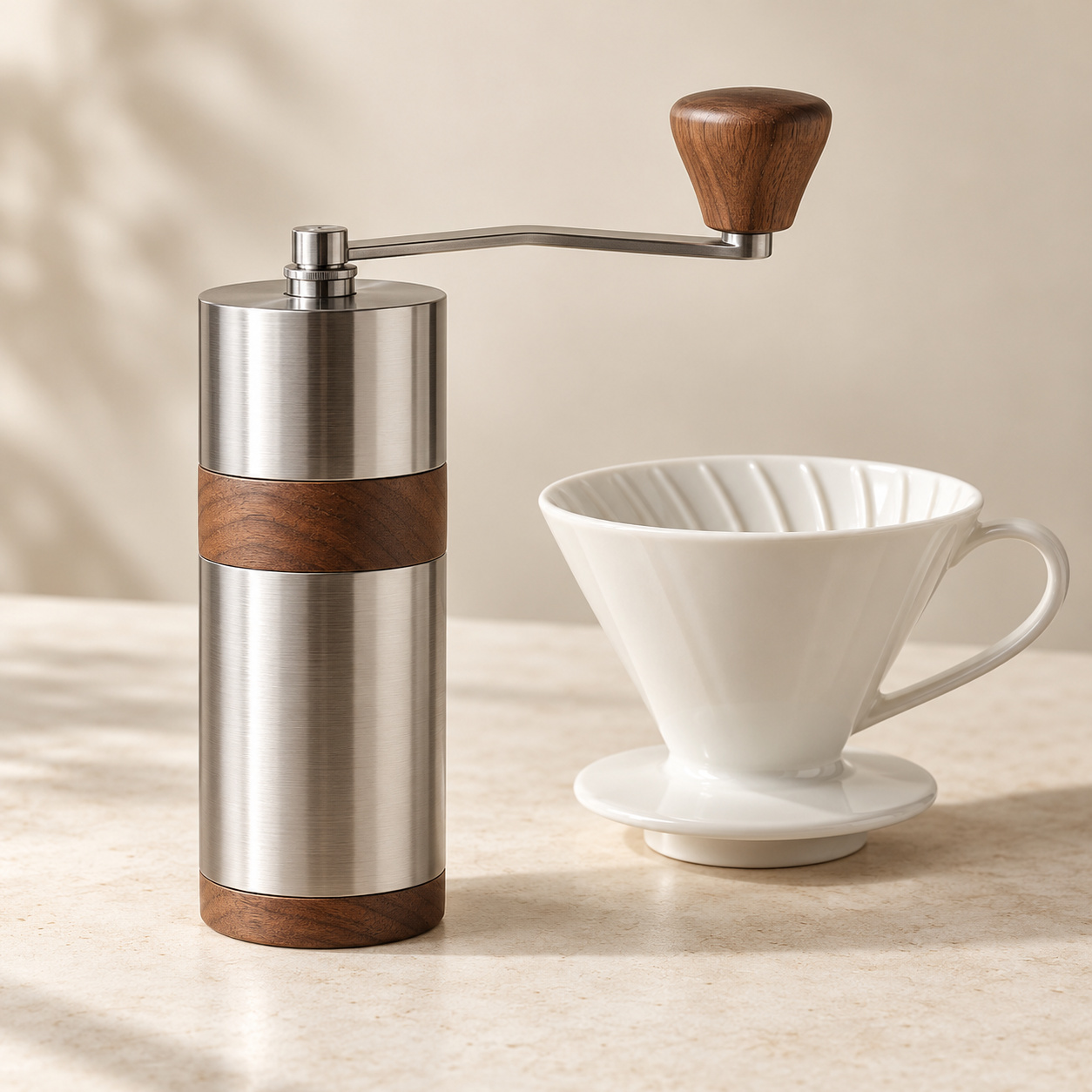 Manual steel and walnut coffee grinder beside a ceramic pour-over dripper